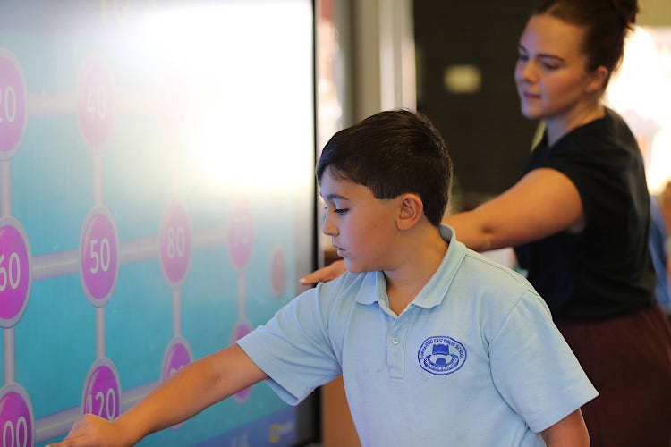 Teacher helping a student on the interactive board