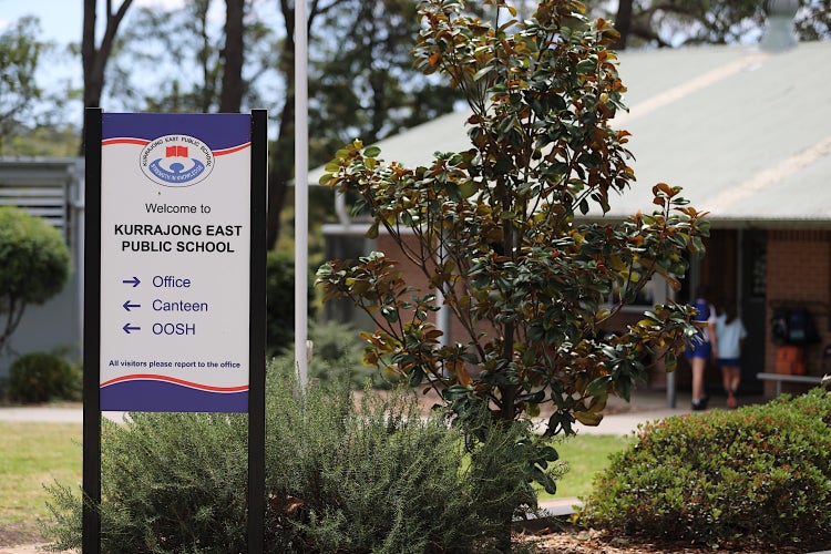 Photo of a school directory sign with a classroom in the background